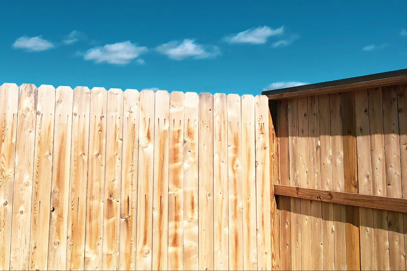 New wood privacy fence installed against a blue Utah sky in Saratoga Springs